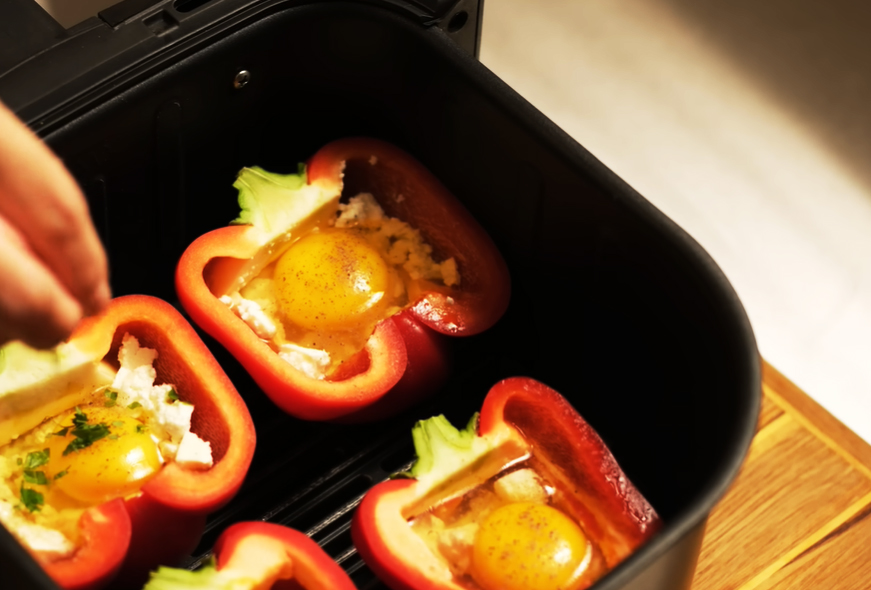 Jetzt kommt der knifflige Teil: Schlage vorsichtig ein Ei in jede Paprikahälfte.