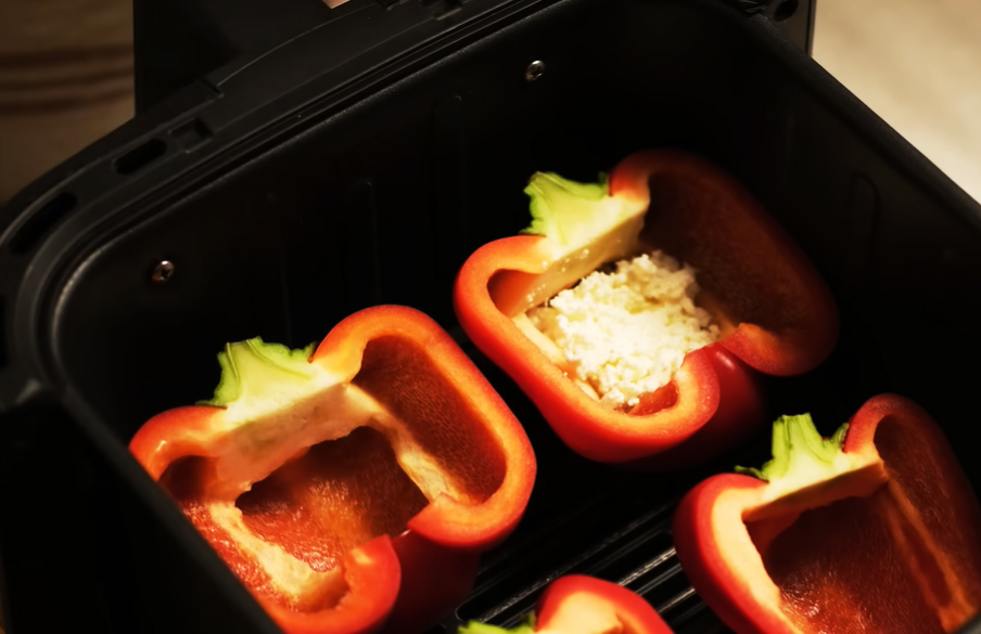 Gib in jede Paprikahälfte 2 Teelöffel zerbröckelten Feta. Drücke ihn leicht an, damit er am Boden haftet. So rutscht später das Ei nicht komplett durch.